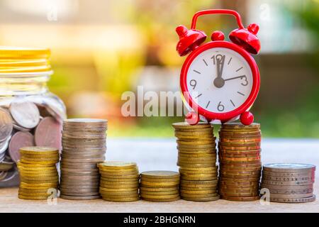 Pig piggy bank and coins and clock on nature blur background. saving money concept. Stock Photo
