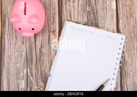 Note book and piggy bank on wood table Stock Photo