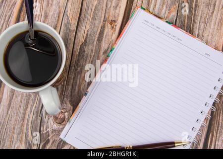 Note book, Eyes Glasses , pen and a cup of coffee on wood table Stock Photo