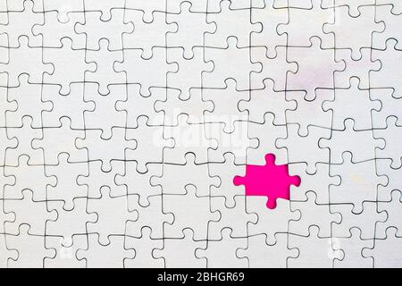 Pink background showing through missing piece in white jigsaw puzzle. Stock Photo