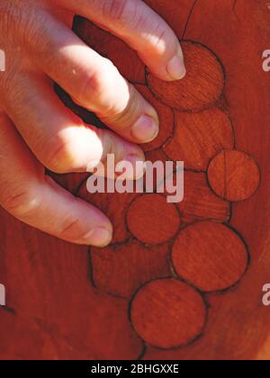 Female hand hold log with circle marks after knots repairing. Red wooden color Stock Photo