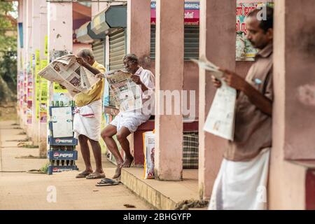 Unidentified indian men reading newspapers outside in Kerala , Southern India Stock Photo