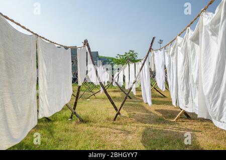 Laundry drying on a rope in the yard in the sunlight Stock Photo