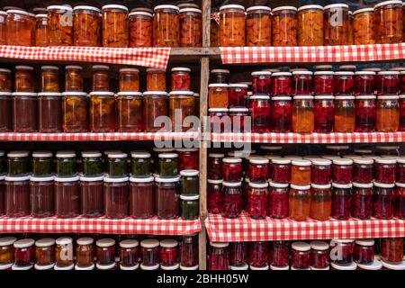Glass jars with various types of natural delicious jam stand in a row on wooden shelves Stock Photo