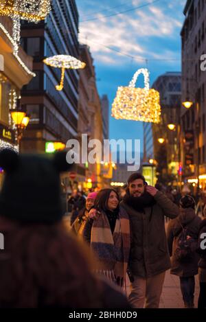 Young couple goes hugging on a shopping street at night Stock Photo
