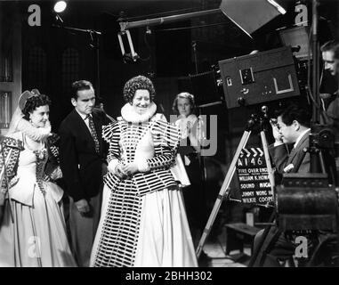 VIVIEN LEIGH and FLORA ROBSON on set candid with Director WILLIAM K. HOWARD Cinematographer JAMES WONG HOWE and Camera Operator WILKIE COOPER during filming of FIRE OVER ENGLAND 1937 novel A.E.W. Mason screenplay Clemence Dane and Sergei Nolbandov music Richard Addinsell producers Erich Pommer and Alexander Korda  London Film Productions / United Artists Stock Photo