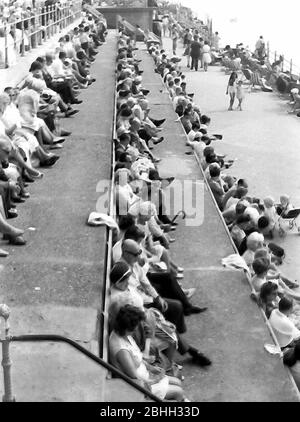 People on holiday sit along the promenade looking at the sea  in Blackpool, Lancashire, England, United Kingdom, in the early 1970's. Stock Photo