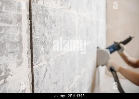 Builder man cutting electrical chase in concrete wall with groove machine diamond crown Stock Photo