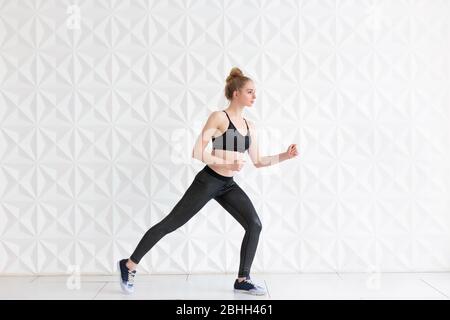 Young fit woman wearing sportswear posing near white wall Stock Photo