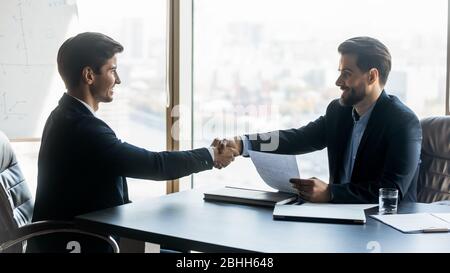 Smiling satisfied hr manager shaking successful candidate hand after interview Stock Photo