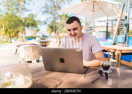 young male work with laptop in cafe outdoors