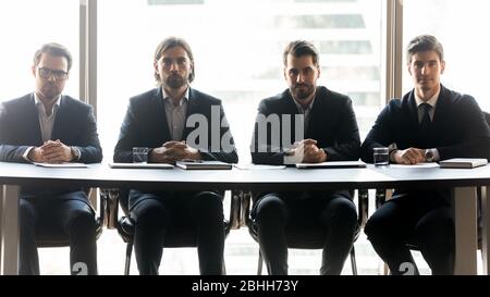 Four serious businessmen sitting in row at meeting Stock Photo
