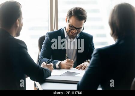 Smiling confident businessman signing contract at group negotiations Stock Photo