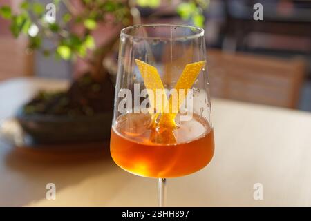 Japanese cocktail with lemon zest, bonsai tree in the background Stock Photo