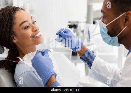 African woman attending dentist, doctor making check up