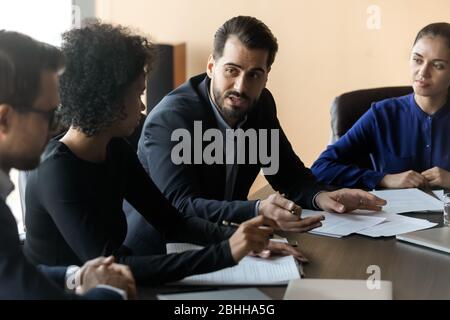 Diverse businesspeople negotiating in boardroom, discussing project plan Stock Photo