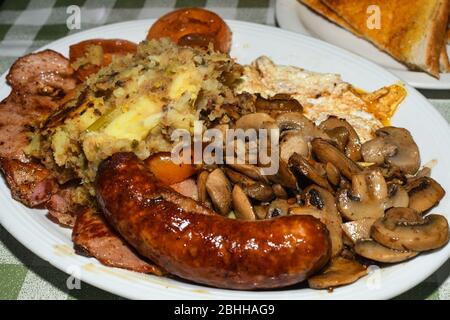 Full English Breakfast including sausages, grilled tomatoes and mushrooms, egg, bacon, baked beans and bread. Stock Photo