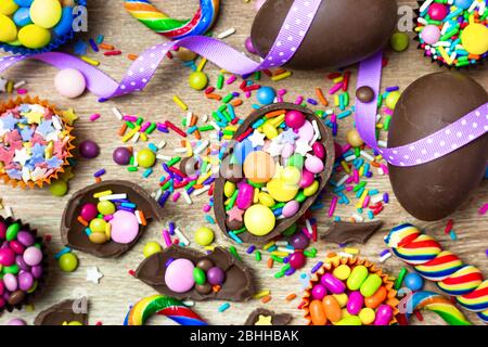 Colorful candies, chocolate eggs and lollipops over wooden background. Top view with copy space. Stock Photo