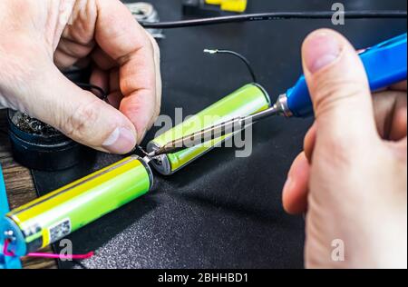 technical master soldering parts with a soldering iron. resin, the smoke, the battery, wires. technical support, repair Stock Photo