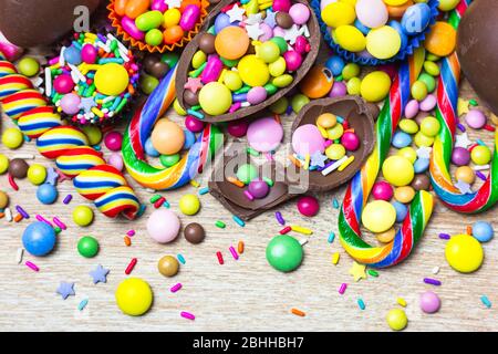 Colorful candies, chocolate eggs and lollipops over wooden background. Top view with copy space. Stock Photo