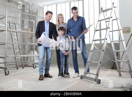 Architect showing house design plans to a family with child. Meeting at interior construction site to talk about house appearance, interior decoration Stock Photo