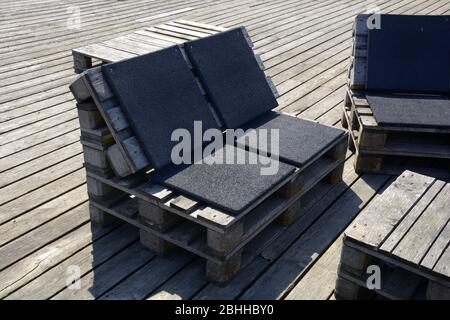 stylish garden or terrace benches made from old wooden storage pallets in summer Stock Photo