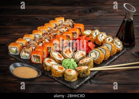 sushi set with sauce and chopsticks on a black board on a dark wooden background Stock Photo