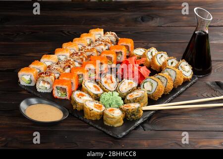 sushi set with sauce and chopsticks on a black board on a dark wooden background Stock Photo