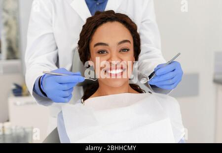 Cheerful african woman and dentist staying behind Stock Photo