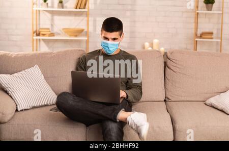 Man wearing surgical mask using his laptop Stock Photo