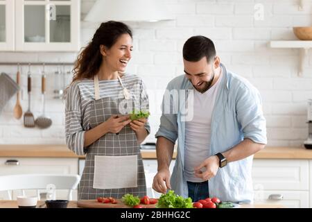 Smiling loving family couple enjoying cooking healthy food. Stock Photo