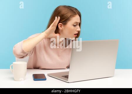 I can't hear, Woman holding arm near ear trying to listen secret talk on video call on laptop, bad internet connection, online conference from home of Stock Photo