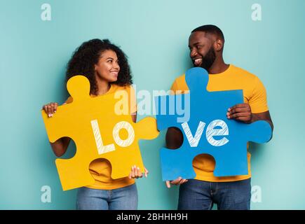 Couple with puzzles in hand over light blue background. Concept of integration, union, relationship and partnership Stock Photo