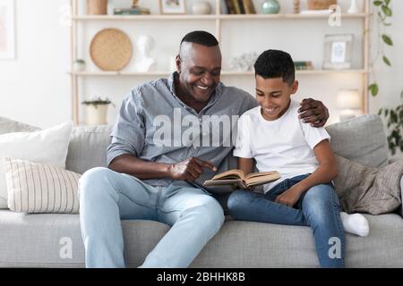 Mature african american man reading book with his grandson at home Stock Photo