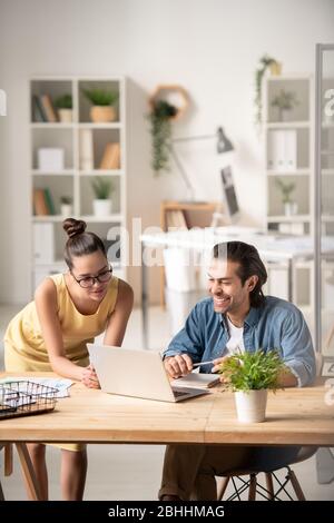 Young business specialists looking at laptop screen and discussing sales strategies for online project in office Stock Photo