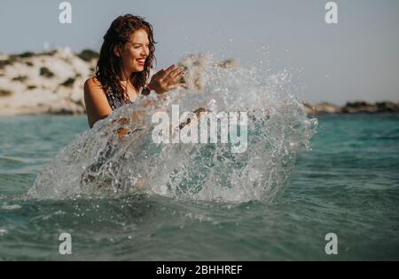 Pretty young woman walking in the warm sea water at summer Stock Photo