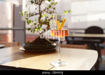 Japanese cocktail with lemon zest, bonsai tree in the background Stock Photo