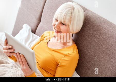 Elderly woman using modern tablet computer at home Stock Photo