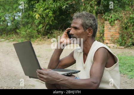 indian rural  farmer using laptop and Mobile Phone Stock Photo