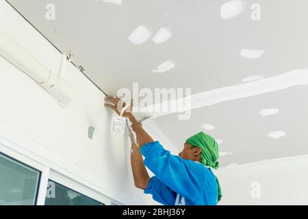 The Thai worker is renewing house's ceiling and painting it again. Hua Hin, Thailand August 3, 2018 Stock Photo