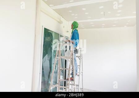 The Thai worker is renewing house's ceiling and painting it again. Hua Hin, Thailand August 3, 2018 Stock Photo