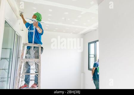 The Thai worker is renewing house's ceiling and painting it again. Hua Hin, Thailand August 3, 2018 Stock Photo