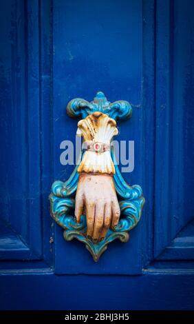 Door knocker in the shape of a hand on a blue door Stock Photo