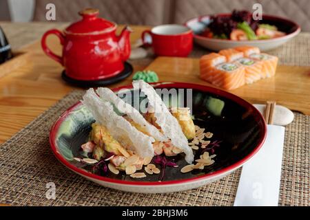 Maki rolls, fried shrimps and tea on table, Japanese cuisine restaurant Stock Photo