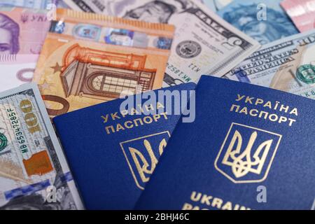 Two Ukrainian biometric passports lie against a background of currencies from different countries of the world, euros, dollars, hryvnias, forints. The Stock Photo