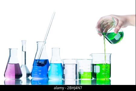 Put green liquid into measuring beaker  with laboratory glassware and liquids of different colors, Flasks and measuring beaker isolated on white backg Stock Photo