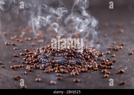 Freshly roasted aromatic coffee beans lie on a dark surface. Fresh morning fragrant drink concept Stock Photo