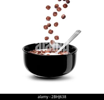 Falling chocolate cereal balls in milk in a black bowl isolated on a white background. Close up with clipping path Stock Photo