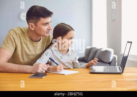 Online learning lessons education school. Father and daughter are doing online education with a teacher using a laptop sitting at home. Stock Photo