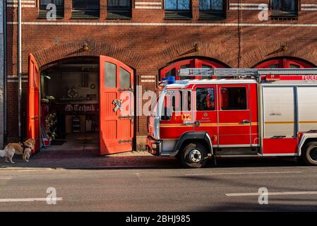 a fire engine stands in front of its fire station with the gate open, fire truck Stock Photo
